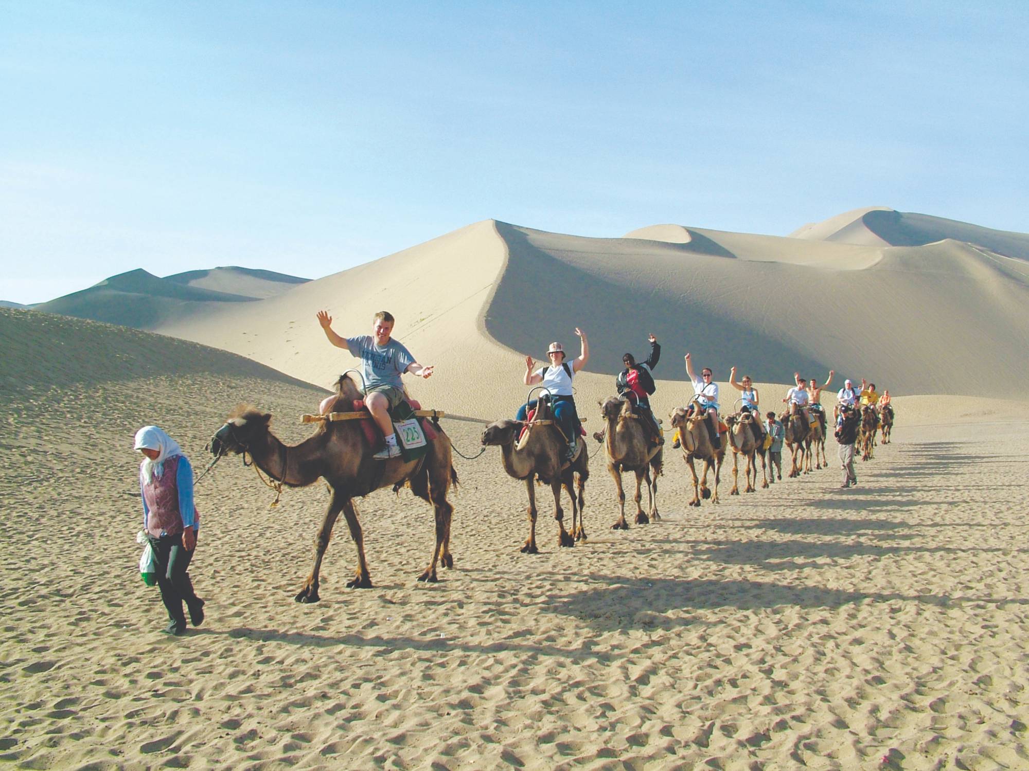 Group of students riding camels through the desert
